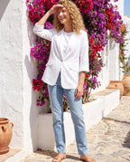 Blazer d'été blanc Constance, porté devant un mur blanchi au bougainvillier