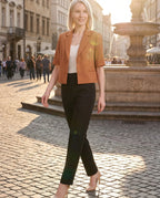 Blazer court caramel Daphné, porté sur une place pavée à l'heure dorée