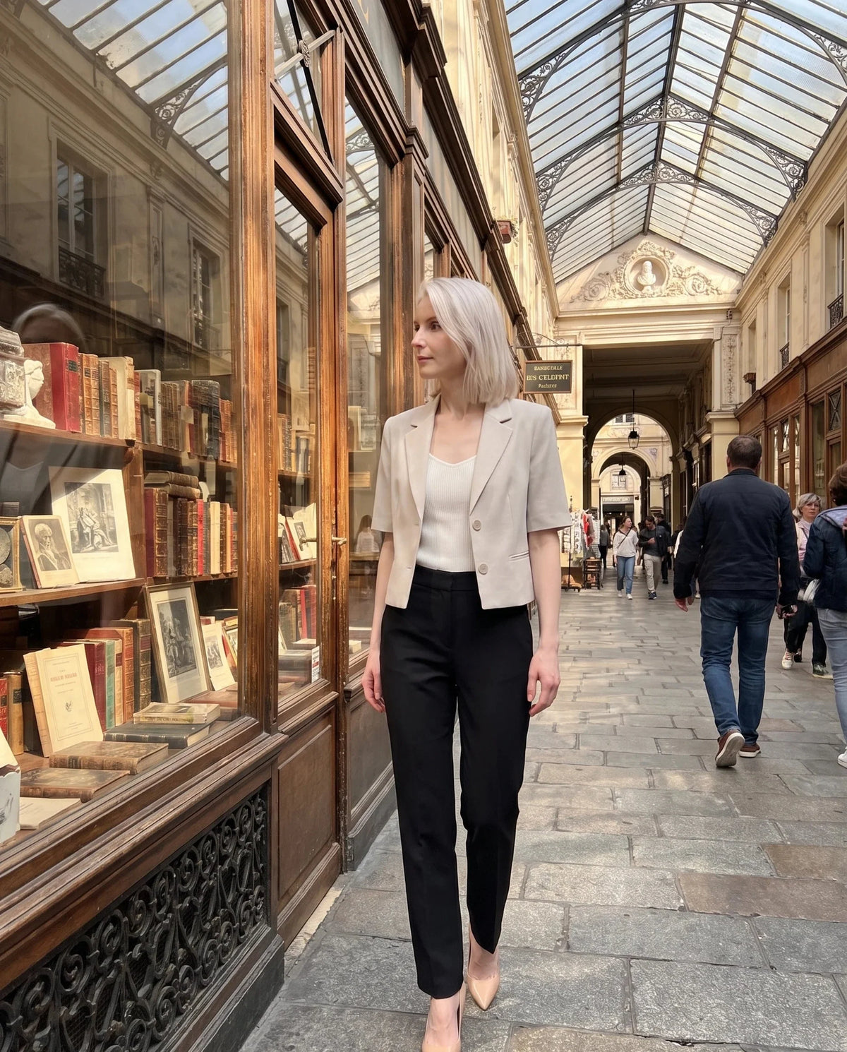 Blazer court grège Daphné, porté dans un passage couvert parisien