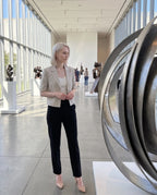 Blazer court grège Daphné, porté dans l'atrium lumineux d'un musée