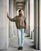 Blouson effet cuir camel Octavie, porté sous une colonnade en pierre claire