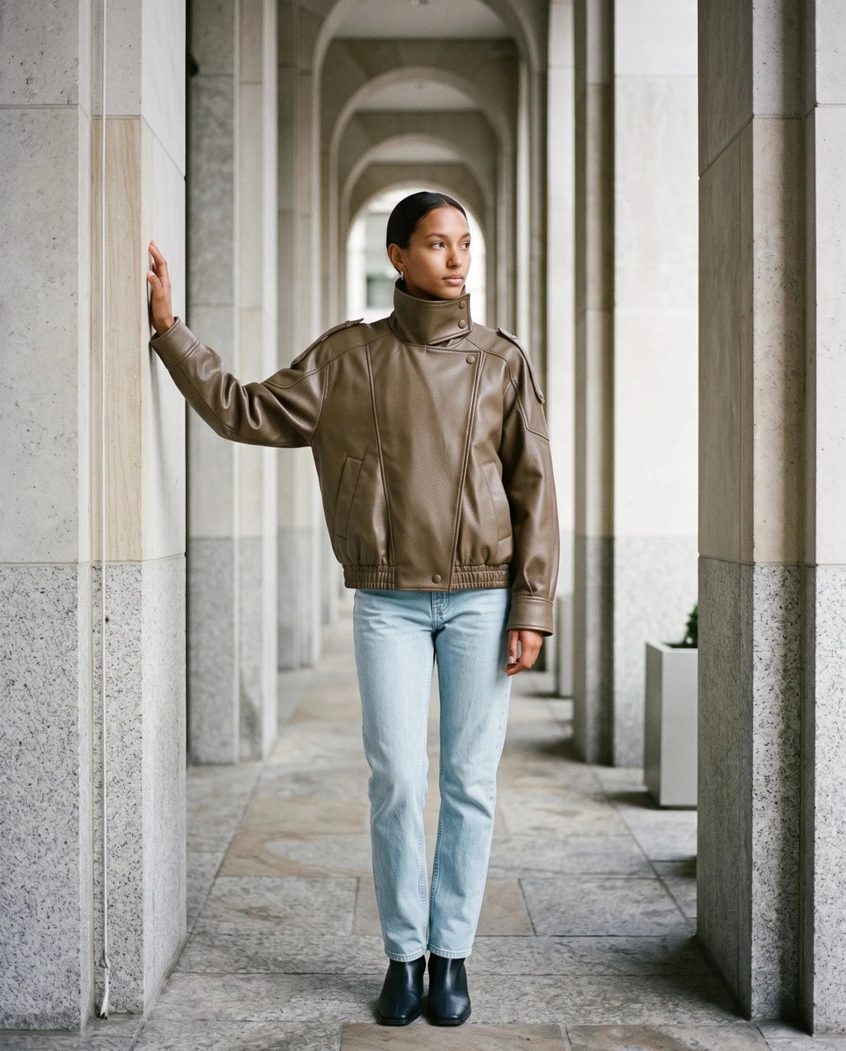 Blouson effet cuir camel Octavie, porté sous une colonnade en pierre claire