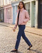 Bomber court à pois rose Célestine, porté dans une rue pavée aux devantures pastel
