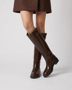 Bottes cavalières hautes effet cuir Bastienne — Chocolat, portées en plan rapproché avec une jupe courte