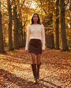 Bottes cavalières hautes effet cuir Bastienne — Chocolat, portées dans une allée de hêtres en automne