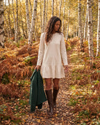 Bottes hautes à talon empilé effet cuir Nicolette — Chocolat, portées sur un sentier forestier aux fougères rousses