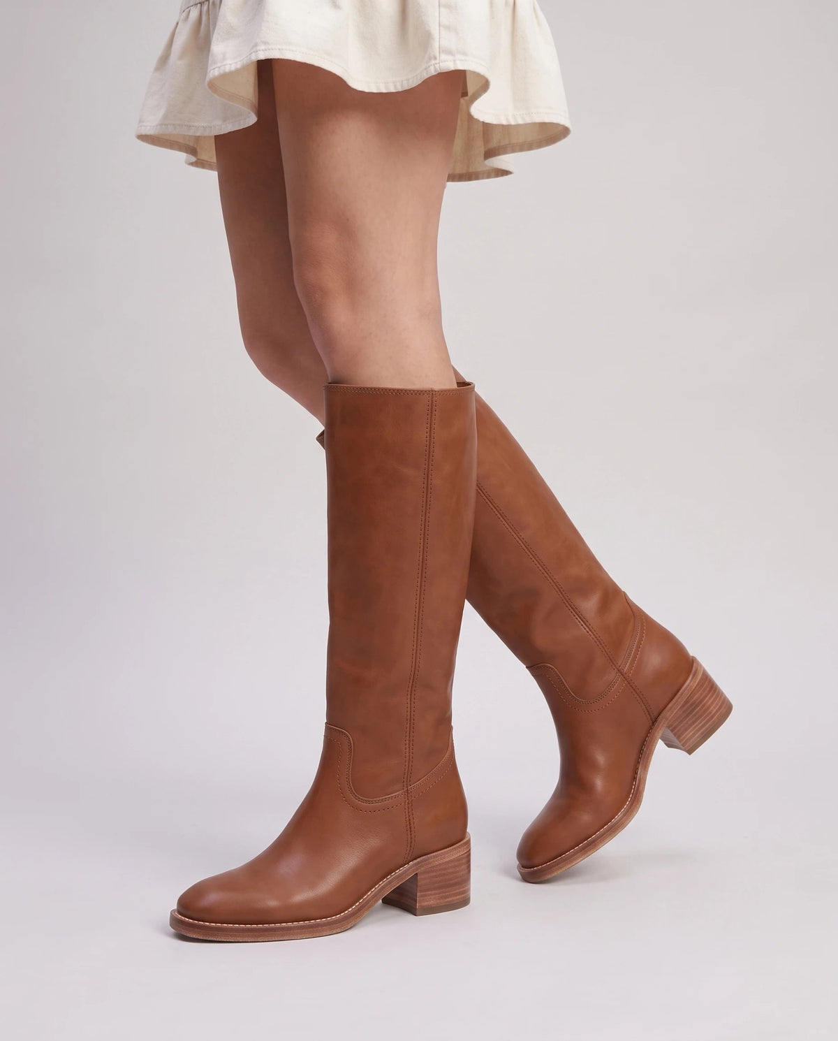 Bottes hautes à talon empilé effet cuir Nicolette — Cognac, portées en plan rapproché avec une robe courte