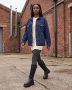 Bottes motardes hautes à zip et boucle Axelle — Noir, portées dans une cour industrielle en briques rouges
