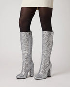 Bottes hautes à paillettes à talon large Éliette — Argent, portées en plan rapproché avec des collants opaques