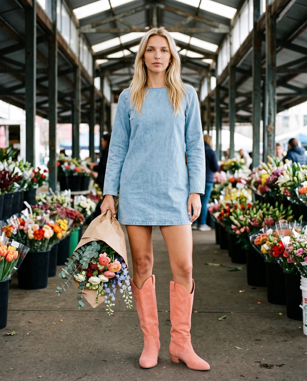 Bottes hautes western en suédine Marjolaine — Corail, portées dans un marché aux fleurs sous halle