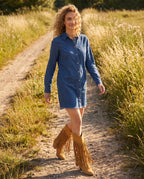 Bottes hautes western à franges cloutées Florentine — Camel, portées sur un chemin bordé d'herbes hautes