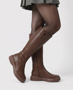 Bottes hautes zippées à semelle épaisse Justine — Chocolat, portées en plan rapproché avec une jupe plissée