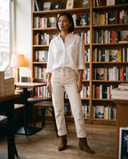 Bottines santiags basses en suédine Yvonne — Chocolat, portées dans une librairie-café aux étagères de bois