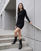 Bottes santiags mi-mollet effet cuir Maurine — Noir, portées sur un escalier de béton d'un immeuble moderne