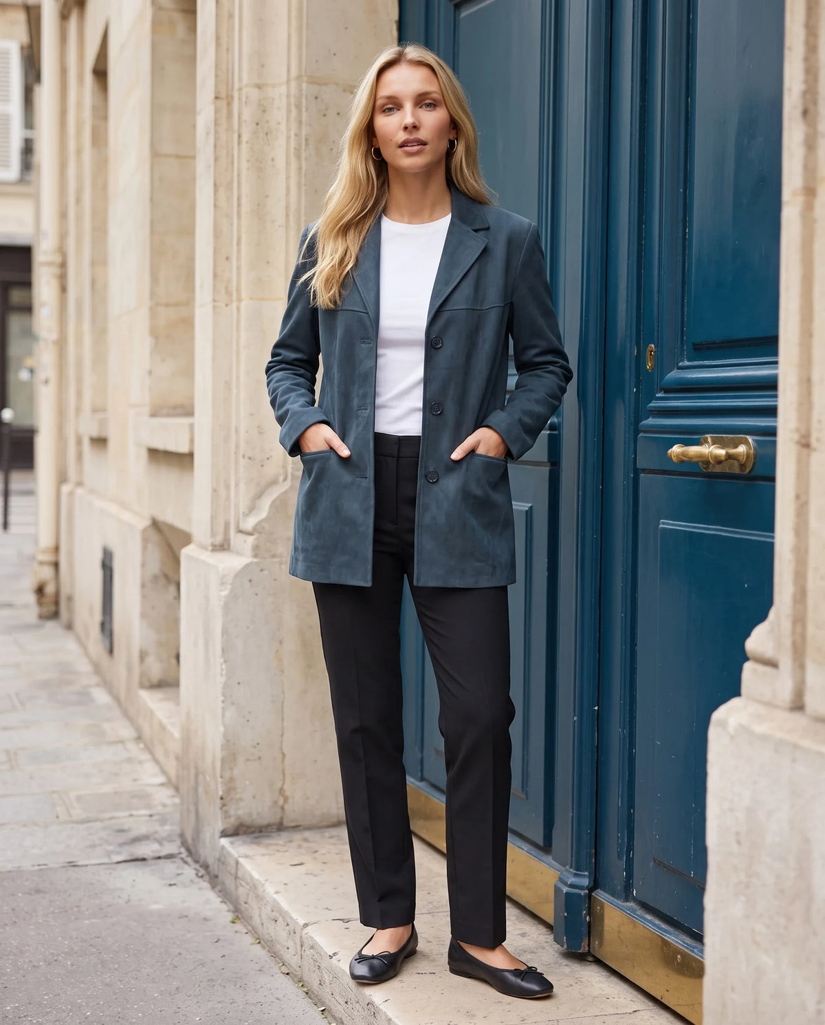 Veste-blazer en suédine bleu pétrole Eugénie, portée devant une porte cochère