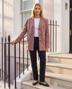 Veste-blazer en suédine vieux rose Eugénie, portée sur un escalier de pierre claire