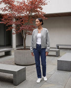 Veste zippée sans col gris chiné Capucine, portée dans une cour minérale à l'érable