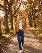 Veste zippée sans col jaune moutarde Capucine, portée sur un chemin aux noyers