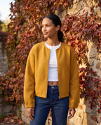 Veste zippée sans col jaune moutarde Capucine, portée devant un mur de vigne vierge rousse