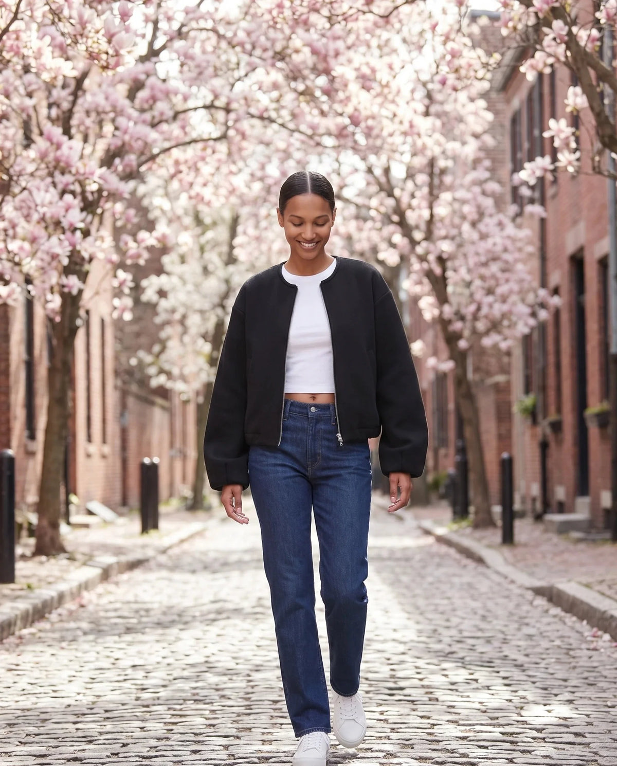 Veste zippée sans col noire Capucine, portée dans une allée de magnolias en fleurs