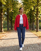 Veste zippée sans col rouge Capucine, portée dans une allée de marronniers