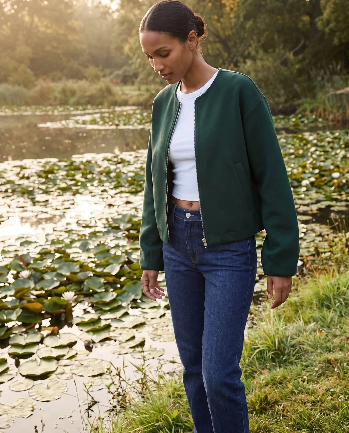 Veste zippée sans col vert bouteille Capucine, portée au bord d'un étang aux nénuphars